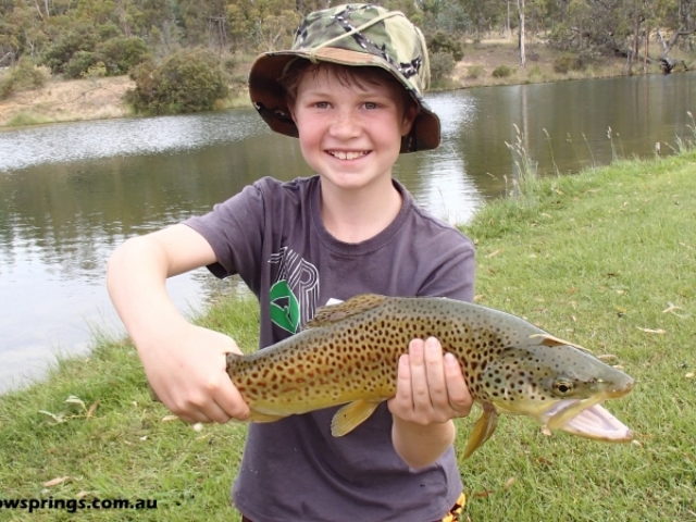 A young man catching a big brown trout