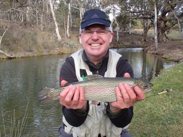 A man with a big smile holding his rainbow trout