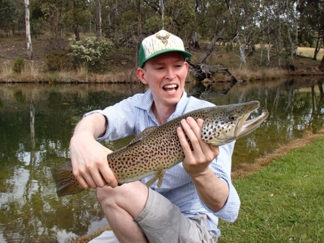 A young man catching a big brown trout