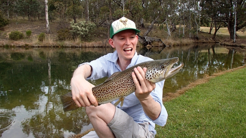 A young man catching a big brown trout