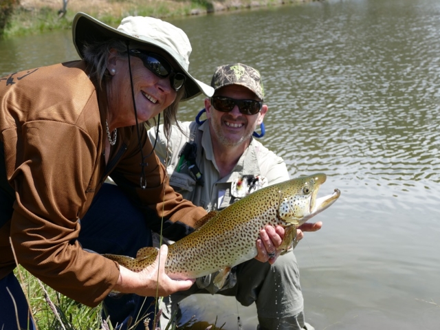 A lady and fishing buddy with a big trout