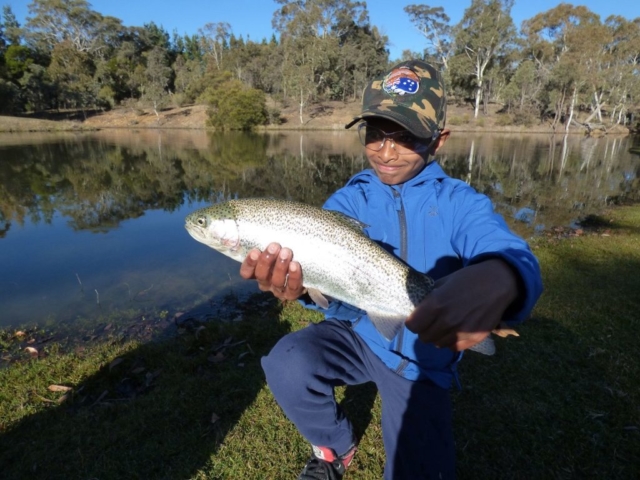 A young man with his shiny silver rainbow trout