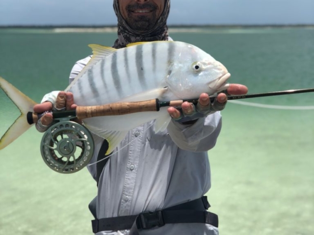 A happy man holding his first Yellowfin Travally on fly