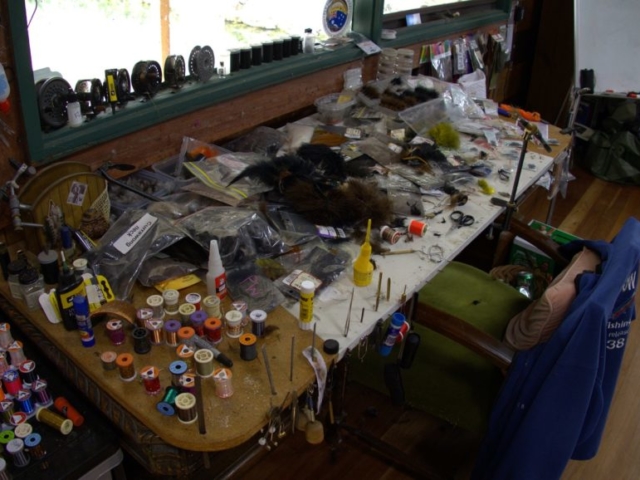 A fly tying table with hooks and feathers everywhere