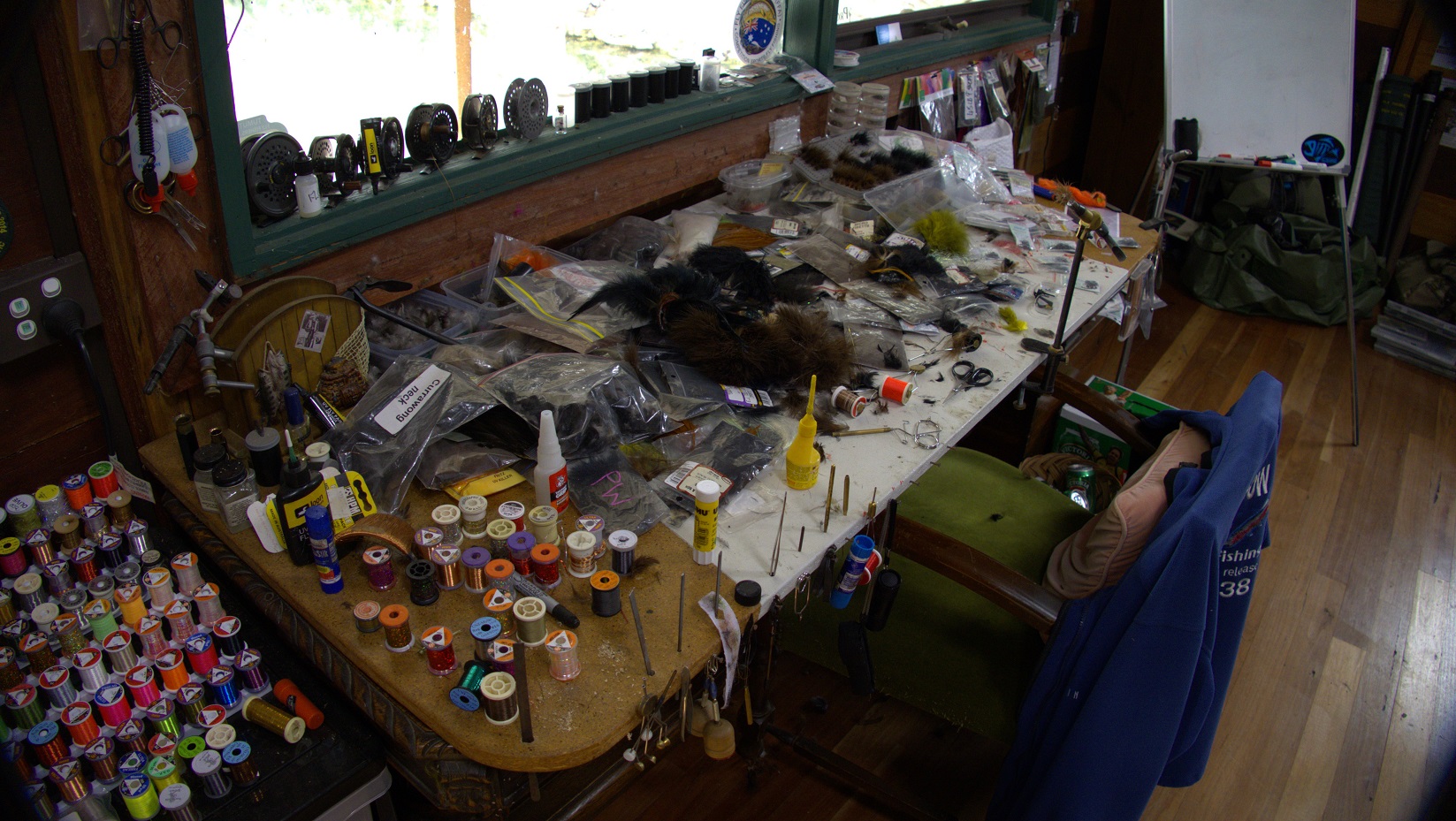 A fly tying table with hooks and feathers everywhere