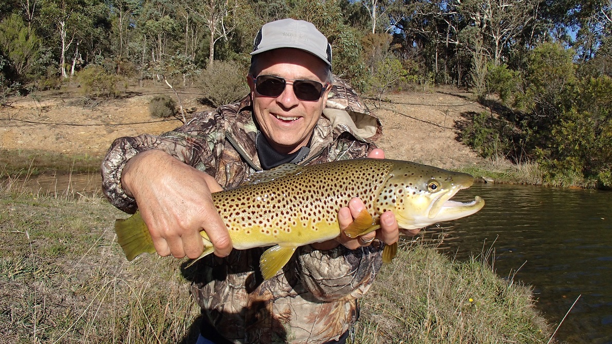 A man in camo gear with his big brown trout