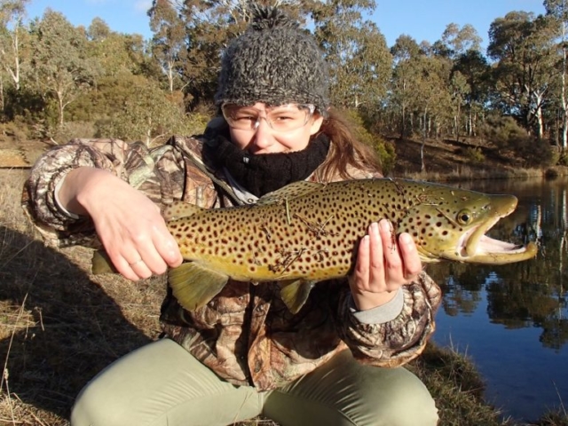 a lady wearing camo gear hunting for trout