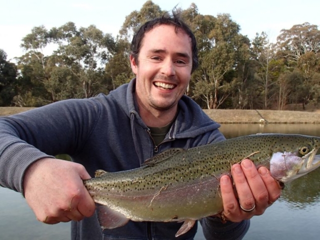 A fly fisherman holding a fat Rainbow Trout