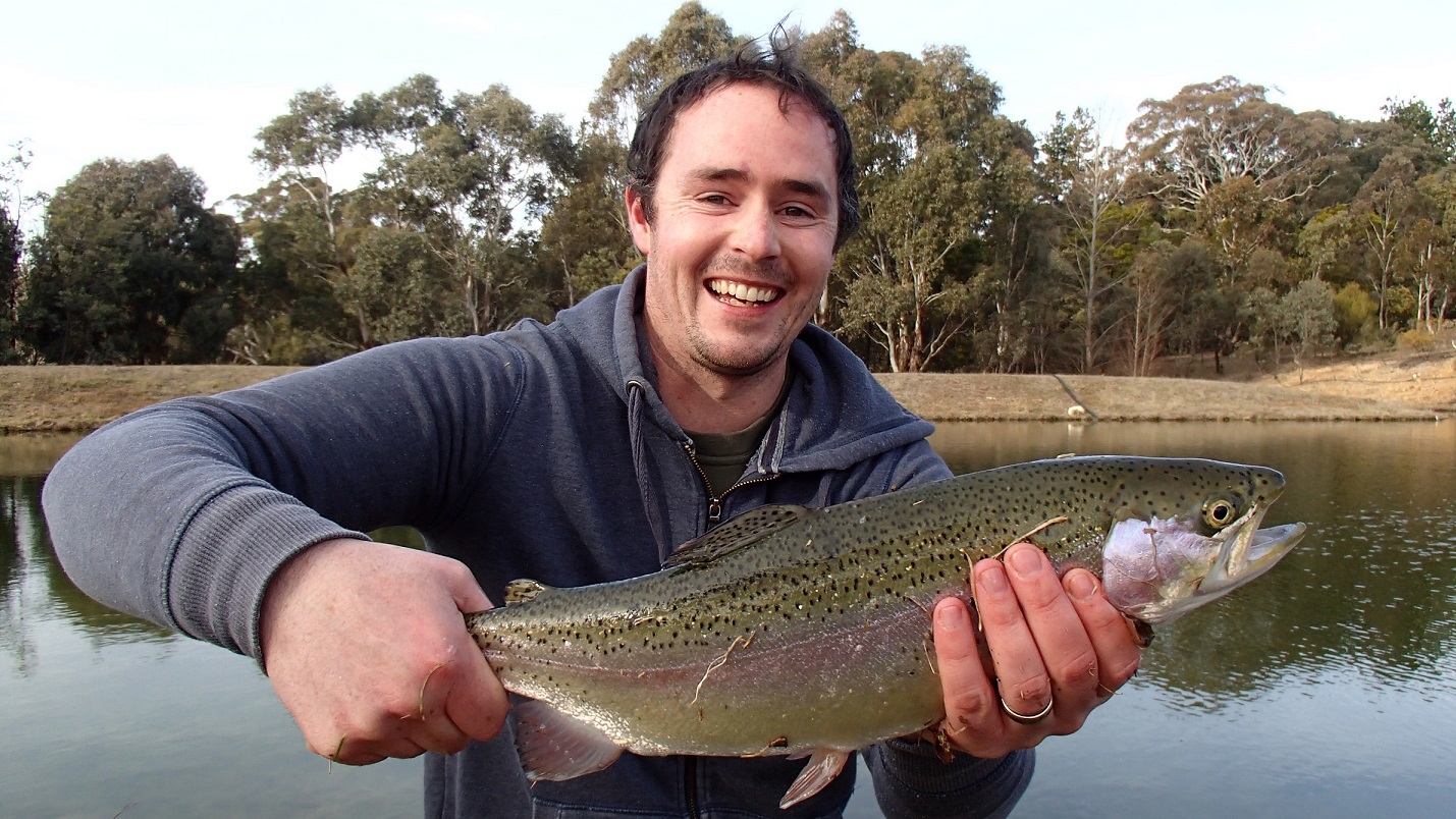 A fly fisherman holding a fat Rainbow Trout