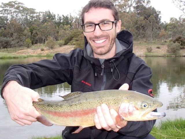 A man holding a nice rainbow at the edge of our lake