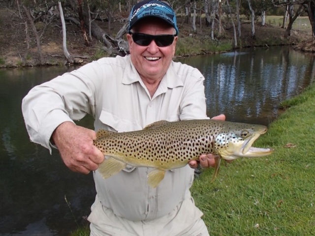 A man by the lake with his brown trout