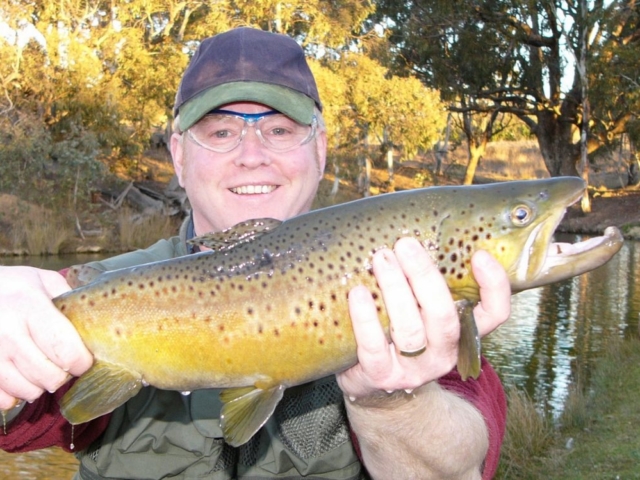 A man showing off his brown trout after learning new techniques